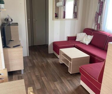 Intérieur salon avec canapé d'angle rouge dans le Mobil Home du camping le Montourey