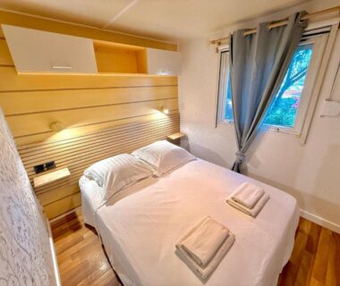 Intérieur chambre avec lit double et serviettes dans le Mobil-Home de Standing Del Carmen