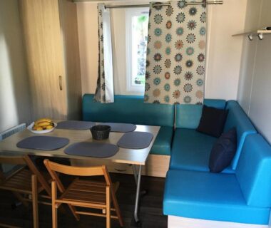 Coin salon avec canapé d'angle et table dans le Mobil Home pour 6 personnes climatisé à quelques minutes des plages