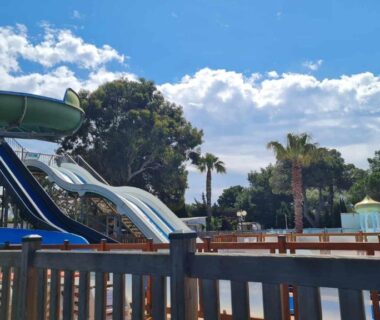 Piscine avec toboggans et palmiers au Camping La Palmeraie