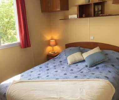 Chambre avec lit double, lampe et fenêtre dans le Mobil Home sans vis a vis