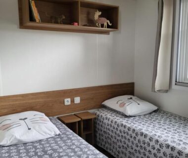 Chambre avec deux lits simples et étagère murale dans le Mobil Home spacieux Camping Mar Estang 4*
