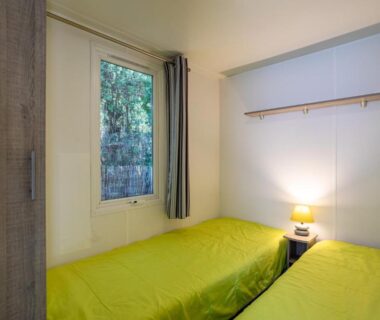 Chambre avec deux lits et fenêtre dans le Mobil Home sur camping avec piscine