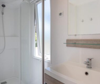 Salle de bains lumineuse avec douche et lavabo dans le Mobil Home sur camping avec piscine