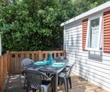 Terrasse en bois avec table et chaises du Mobil Home sur camping avec piscine