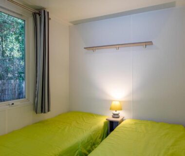 Chambre avec deux lits et fenêtre dans le Mobil Home sur camping avec piscine