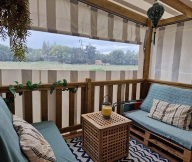 Terrasse couverte avec salon extérieur et vue sur plan d'eau du Mobil Home tout confort