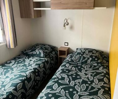 Intérieur chambre avec deux lits et rangements dans le Mobil-Home tout confort avec Clim