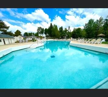 Piscine extérieure avec transats et ciel bleu au Domaine de Dugny