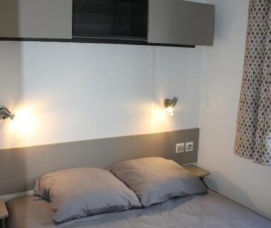 Chambre avec lit double et lampes de chevet dans le mobil-home