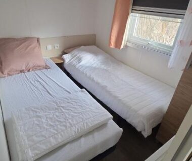 Chambre avec deux lits simples et fenêtre dans le Mobil-home