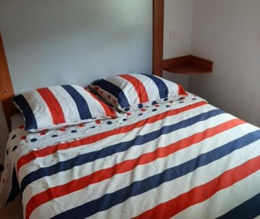 Chambre avec lit double et couette rayée dans le Mobil home