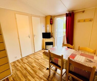 Intérieur avec table, chaises et télévision dans le mobil-home 159 du camping Les Clarines