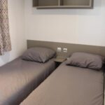 Chambre intérieure avec deux lits simples dans le mobil-home