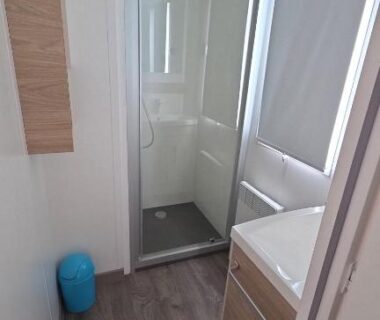 Salle de bains avec cabine de douche et lavabo dans le mobil-home