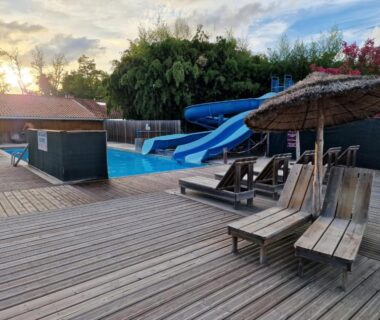Terrasse au bord de la piscine avec toboggan et transats du mobil-home