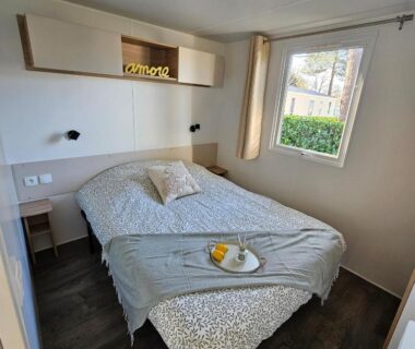 Chambre avec lit double et fenêtre dans le mobil home Domaine de Kerlann