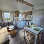 Salon et kitchenette avec coin repas dans le mobil-home 2 ch 4-6 pers du Domaine de Kerlann