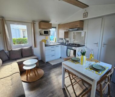 Salon et kitchenette avec coin repas dans le mobil-home 2 ch 4-6 pers du Domaine de Kerlann