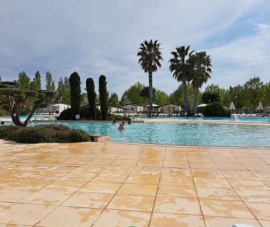 Bord de piscine avec transats et palmiers au mobil home 2 chambres camping 4 étoiles Vias
