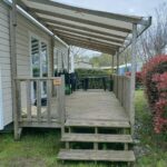 Terrasse surélevée en bois avec marches et toit couvert au Mobil home