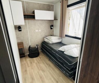 Chambre avec lit simple fenêtre et rangements dans le mobil home 253 du Camping La Réserve à Gastes