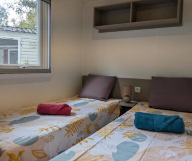 Chambre avec deux lits et serviettes dans le mobil home 262 au Camping Siblu La Réserve