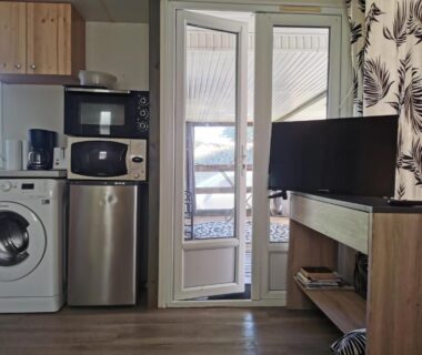 Coin cuisine avec lave-linge réfrigérateur micro-ondes et télévision dans le Mobil-home