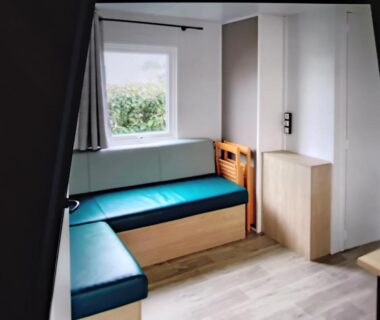 Intérieur avec banquette bleue et fenêtre dans le mobil home