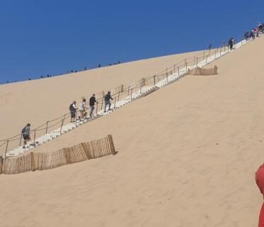 Dune de sable avec escalier et promeneurs près du Mobil-home