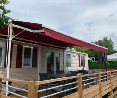 Terrasse du camping avec store rouge et salon extérieur du Mobil home