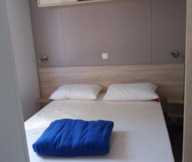 Chambre avec lit double et couverture bleue dans le mobil home 3 chambres