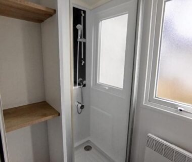 Salle d'eau avec douche cabine étagères et fenêtre dans le Mobil-home 3 chambres