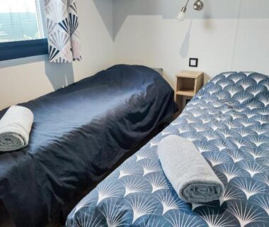 Chambre avec deux lits simples et serviettes roulées du Mobil home 3 chambres Accès direct plage 4 Etoiles