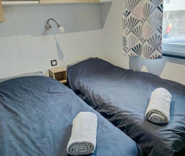 Chambre avec deux lits et serviettes dans le Mobil home 3 chambres Accès direct plage 4 Etoiles