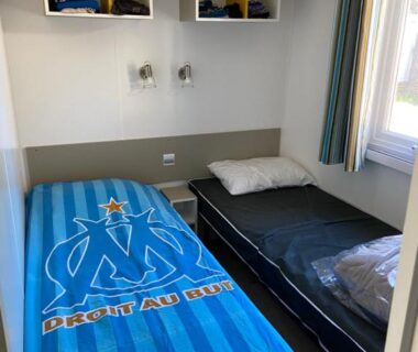Chambre avec deux lits et couverture OM dans le mobil home 3 chambres du camping Le Grau du Roi