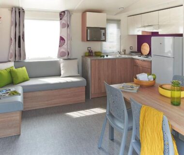 Séjour avec canapé et kitchenette dans le mobil home 3 chambres climatisé du Domaine du Vieux Moulin