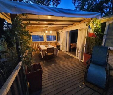 Terrasse en bois éclairée avec table et fauteuils du Mobil-home 3 chambres climatisé sur le domaine Rivages des Landes