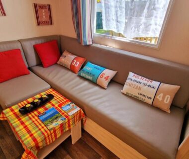 Coin salon avec banquette et coussins près de la fenêtre dans le mobil-home 3 chambres climatisé Rivages des Landes