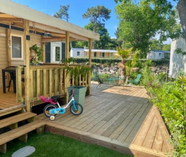 Terrasse en bois avec trottinette et végétation du Mobil home 3 chb tout confort Espace Enfants Claouey Cap Ferret