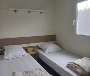 Intérieur de la chambre avec deux lits simples et couvertures dans le Mobil-home 323