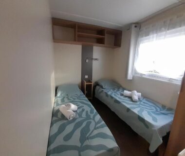 Chambre avec deux lits simples et serviettes dans le mobil-home 331 au camping Pipiou Siblu