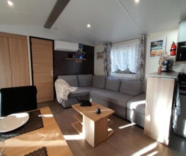 Séjour avec canapé et coin cuisine dans le mobil-home 331 au camping Pipiou Siblu
