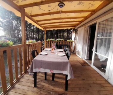 Terrasse couverte en bois avec table dressée du Mobil-home 331 au camping Pipiou Siblu