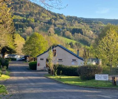 Allée bordée de chalets avec montagne en arrière-plan au Mobil-home 3ch le Per Malou Camping Les Clarines