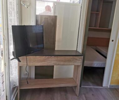 Pièce intérieure avec bureau télévision et chambre visible dans le Mobil-home