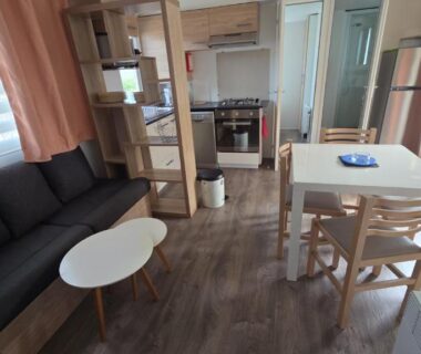 Séjour avec canapé table à manger et kitchenette dans le mobil-home