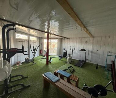 Salle de sport intérieure avec tapis de course vélos elliptiques bancs et haltères dans le Mobil-home