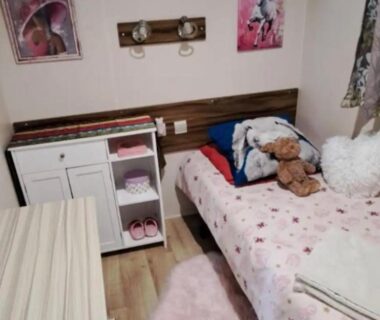 Chambre avec lit simple peluches et meuble de rangement dans le mobil home