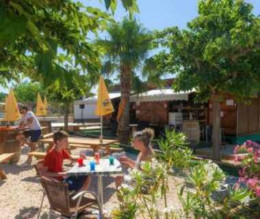 Terrasse extérieure avec tables en bois et parasols au Mobil home 4 à 6 personnes du camping PORT LA NOUVELLE